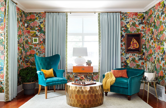 Living room with pale blue curtains, botanical wallpaper and teal velvet armchairs