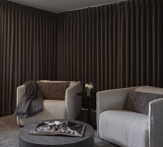 Living room with charcoal extra wide curtains covering a whole wall behind gray sofas